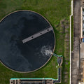 Aerial view of a water treatment plant with a large circular tank and industrial equipment.
